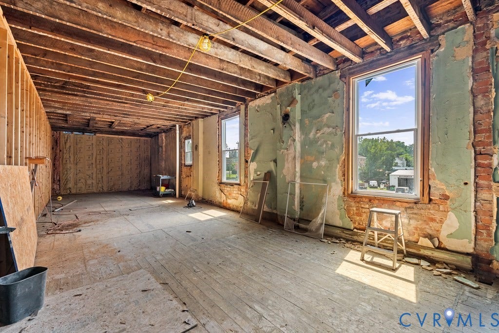 Exposed brick walls, wood-beam ceiling, wood-plank flooring, and multiple windows