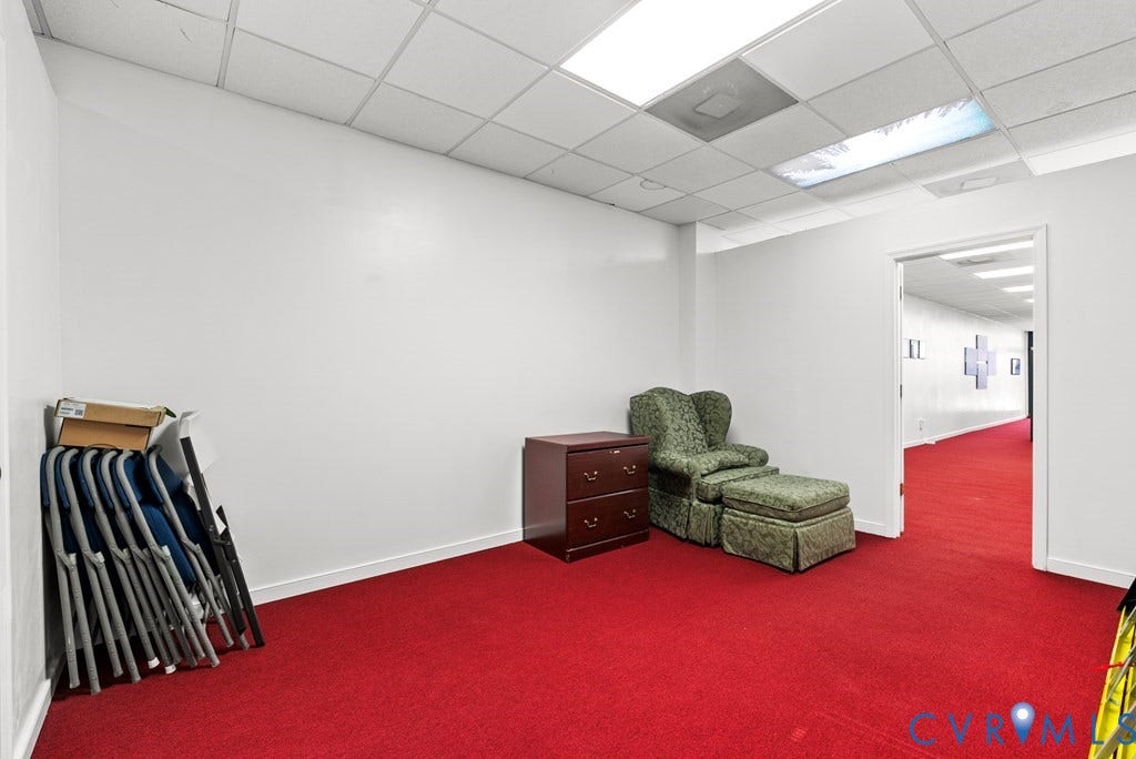 Wall-to-wall red carpeting, white painted walls, and a dropped ceiling with integrated lighting