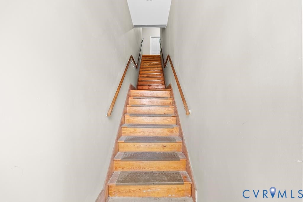 Staircase with wood-finish treads, light-toned risers, and a continuous wood handrail