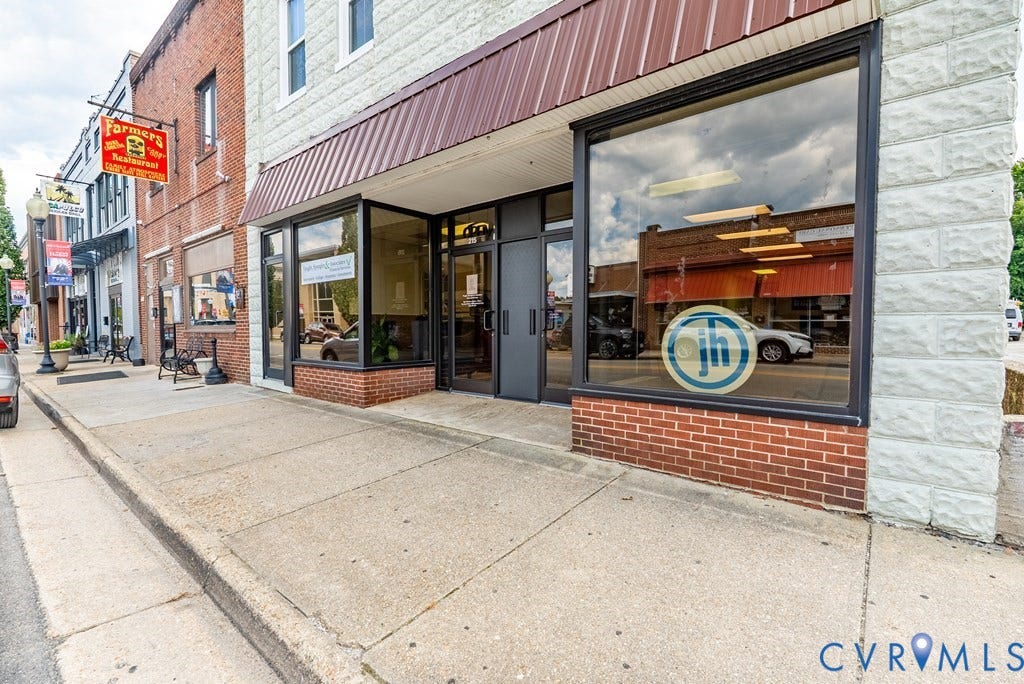 Brick and stone facade with large storefront windows and a brown awning