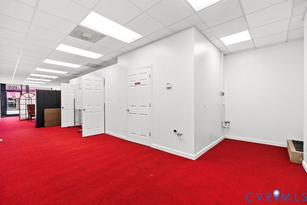 Recessed lighting, drop ceiling, white walls, red carpeting, multiple paneled doors