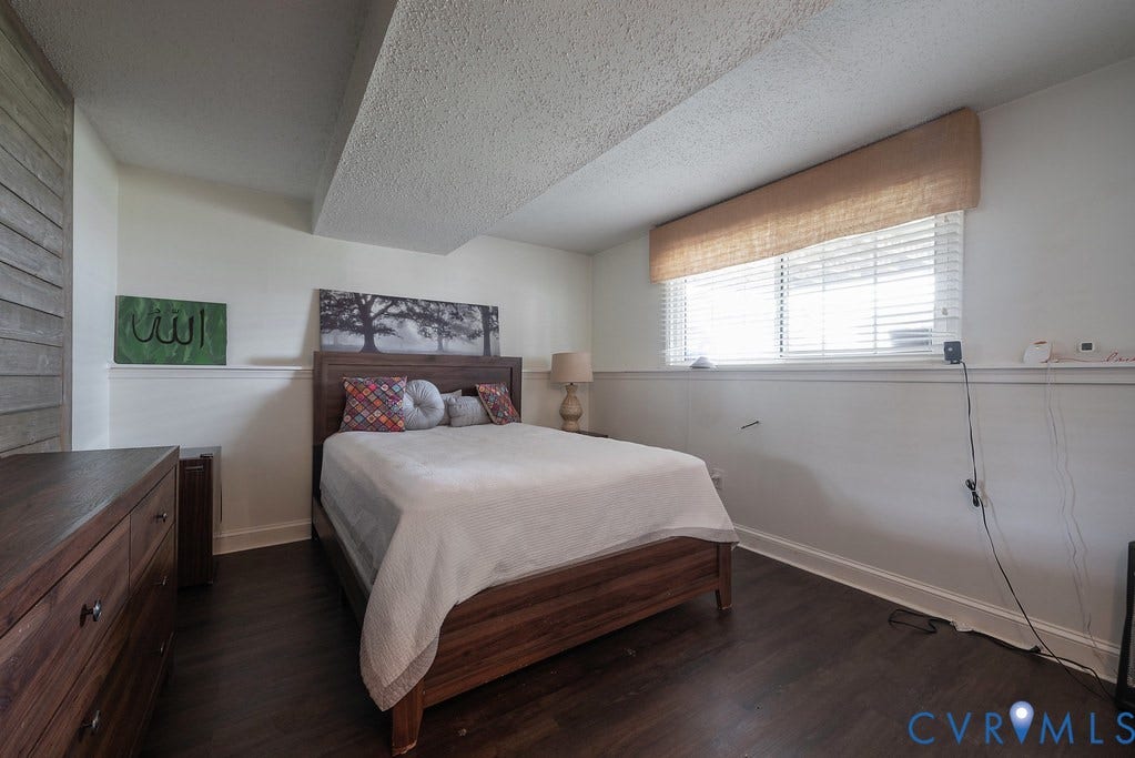 Dark wood-finish flooring, paneled interior door, white trim, recessed lighting, and wall-mounted handrail