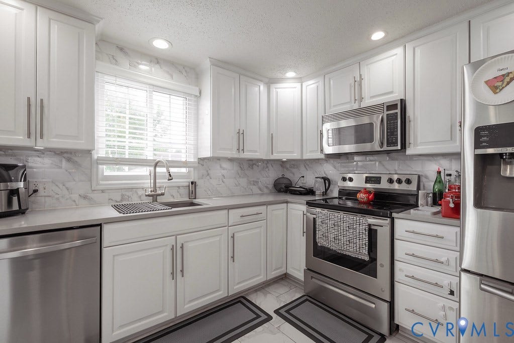 White shaker cabinetry, light-toned countertops, tile flooring, built-in recessed lighting, and decorative wall molding
