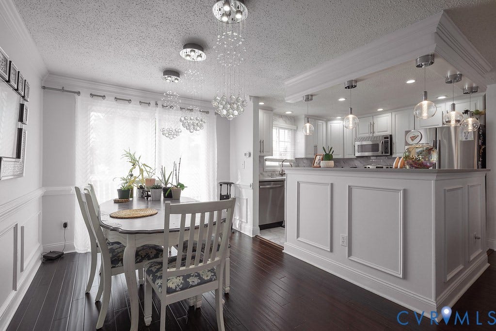 Dark wood-finish flooring, wainscoting with crown molding, frosted glass sliding doors, recessed lighting, and a kitchen counter with light-toned surface