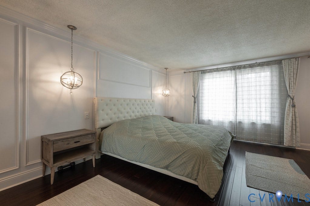 Dark wood-finish flooring throughout, bright window with drapes, built-in wall sconce, and recessed laundry appliance