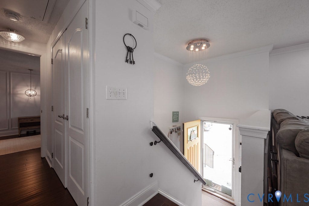 Entryway featuring a paneled door, wood-finish flooring, and a staircase with painted risers and dark wood treads