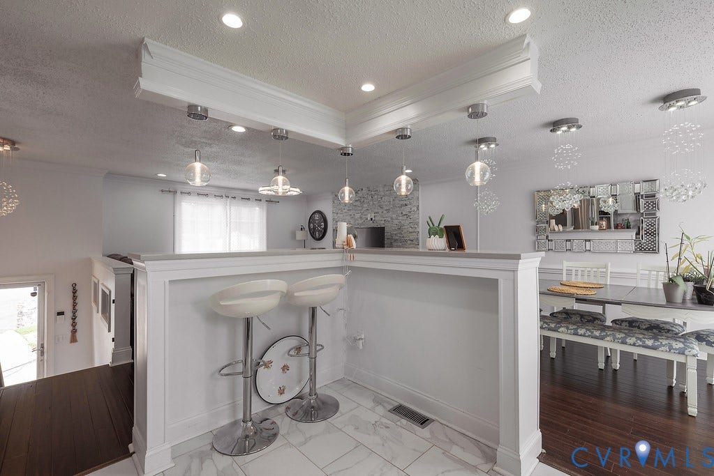 Kitchen featuring white cabinetry, stainless steel appliances, light-toned countertops, and a white tile backsplash