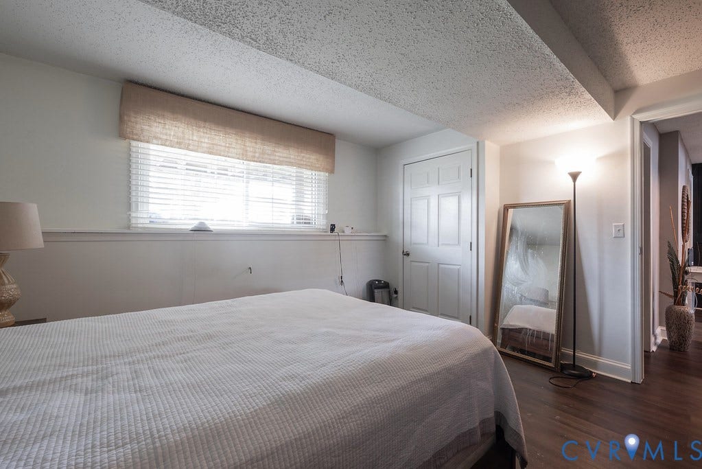 Dark wood-finish flooring with white baseboards and a contrasting accent wall featuring horizontal wood paneling