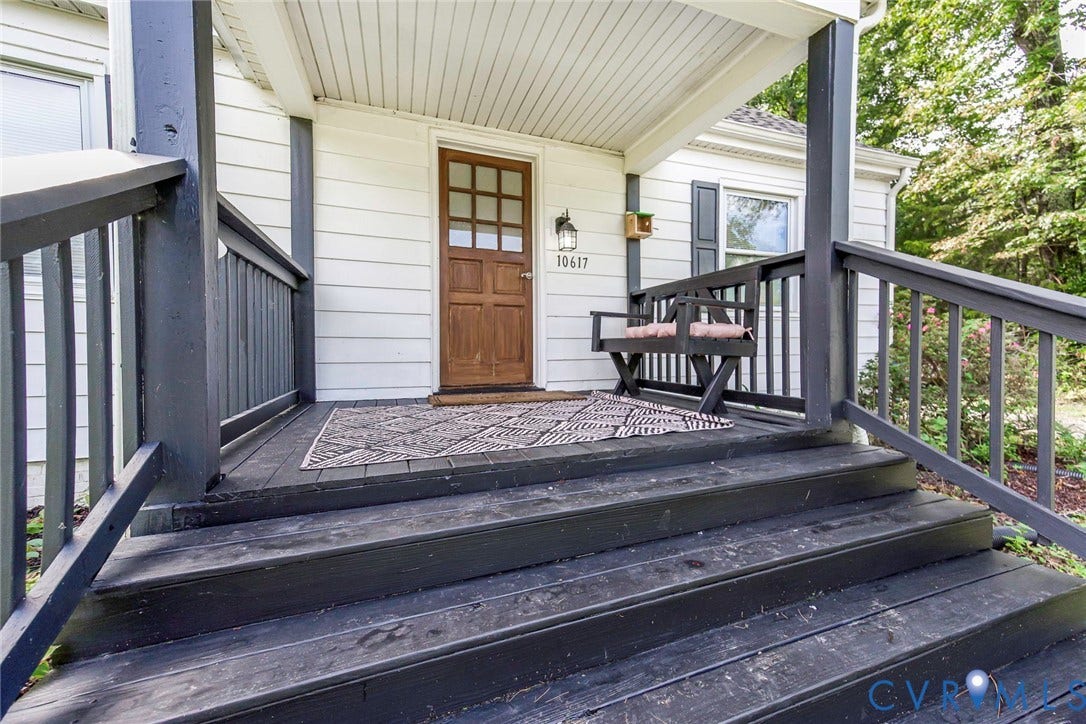 Covered porch entry featuring a wood-panel door with glass inserts, wall-mounted exterior light fixture, and horizontal siding