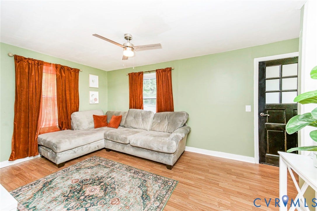 Wood-finish flooring, ceiling fan with light fixture, and a paneled interior door with frosted glass inserts