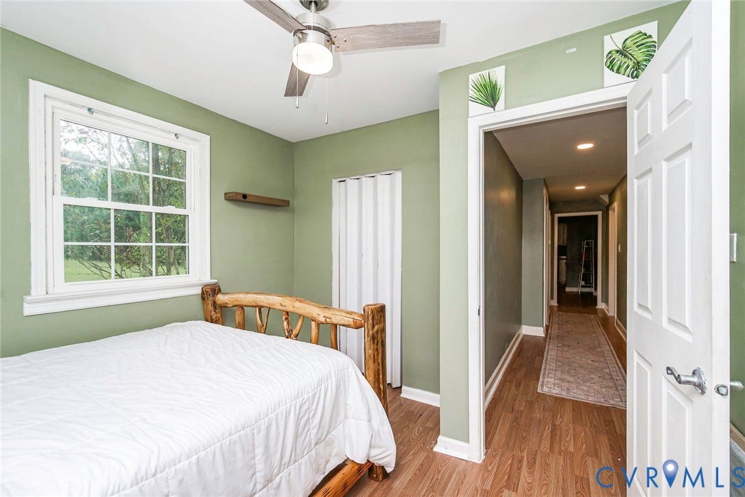 Wood-finish flooring throughout, ceiling fan with integrated lighting, and a white paneled door