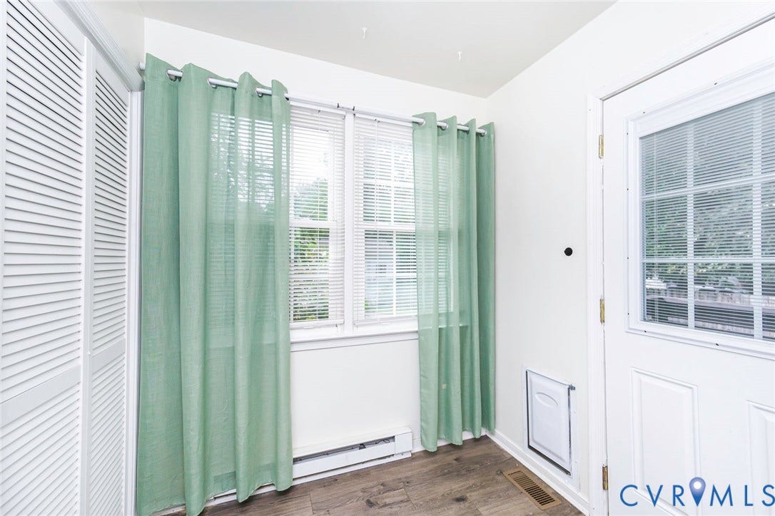 Wood-finish flooring, white louvered doors, and a paneled entry door with glass inserts