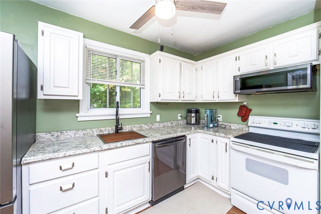 White cabinetry, granite-style countertops, stainless steel dishwasher, over-range microwave, and a ceiling fan