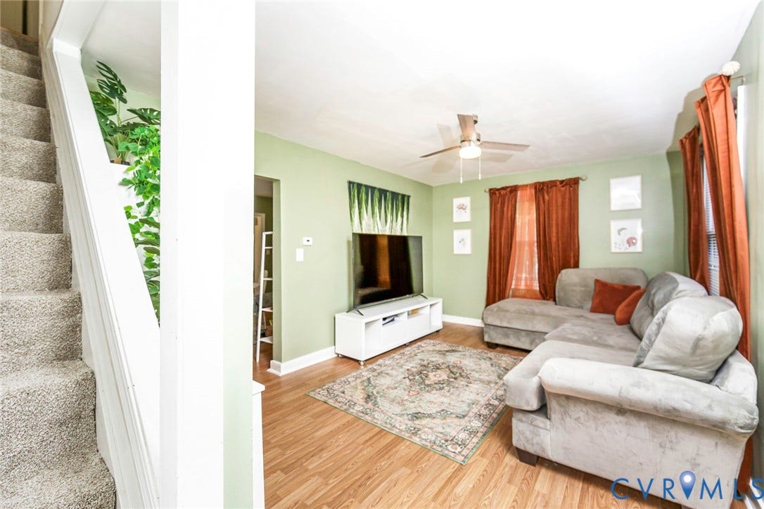 Living area featuring wood-finish flooring, a ceiling fan, and a built-in media console