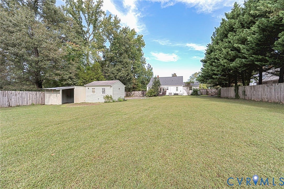 Expansive lawn featuring a detached shed, a separate open-sided structure, and a perimeter fence. 1.07 acres