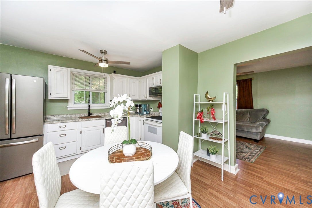 Kitchen featuring wood-finish flooring, white cabinetry, and granite countertops