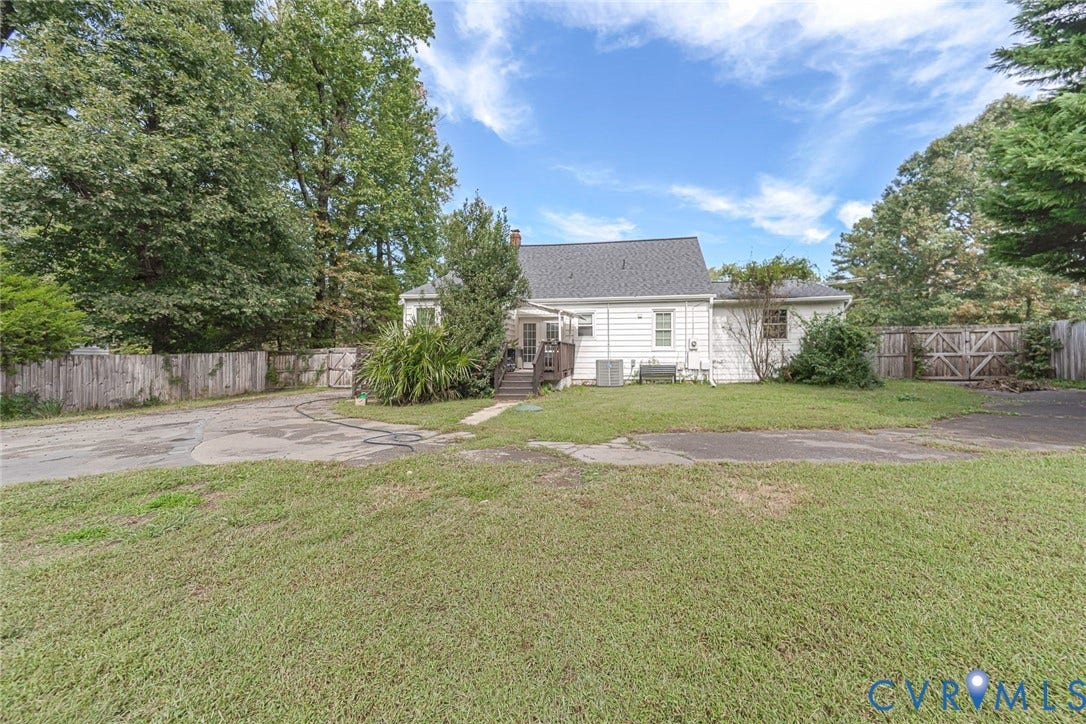 Expansive grassy yard with mature trees and a wooden fence