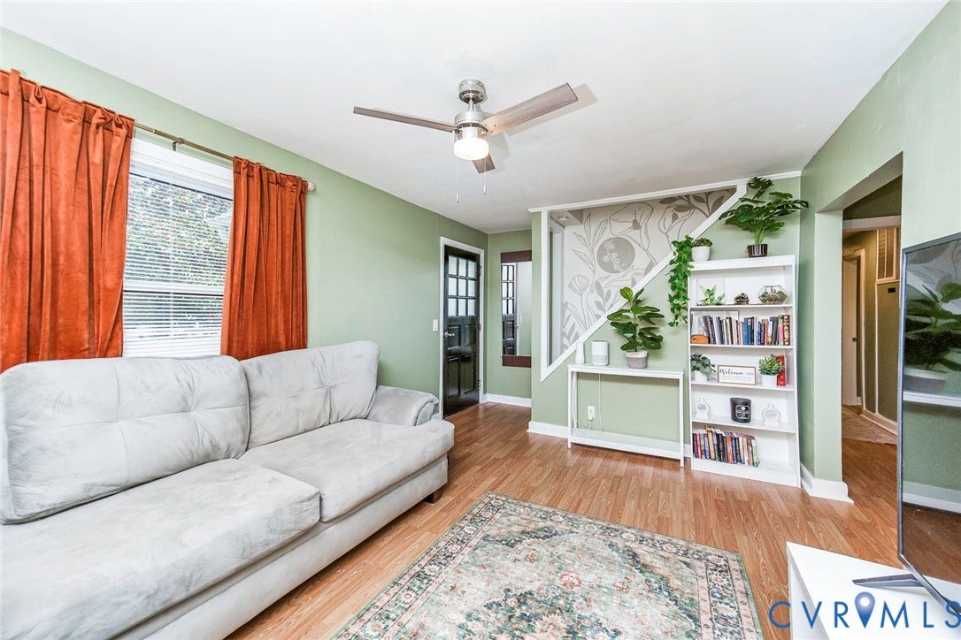 Wood-finish flooring throughout, ceiling fan with light fixture, and a built-in bookshelf