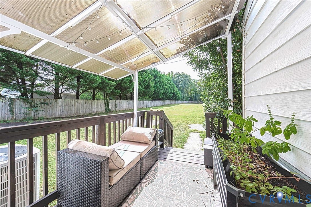 Covered deck featuring a clear panel roof and dark wood railings
