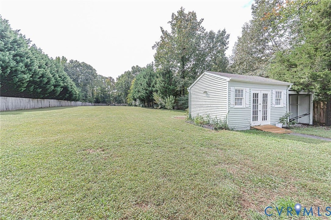 Expansive grassy yard with a privacy fence and mature trees