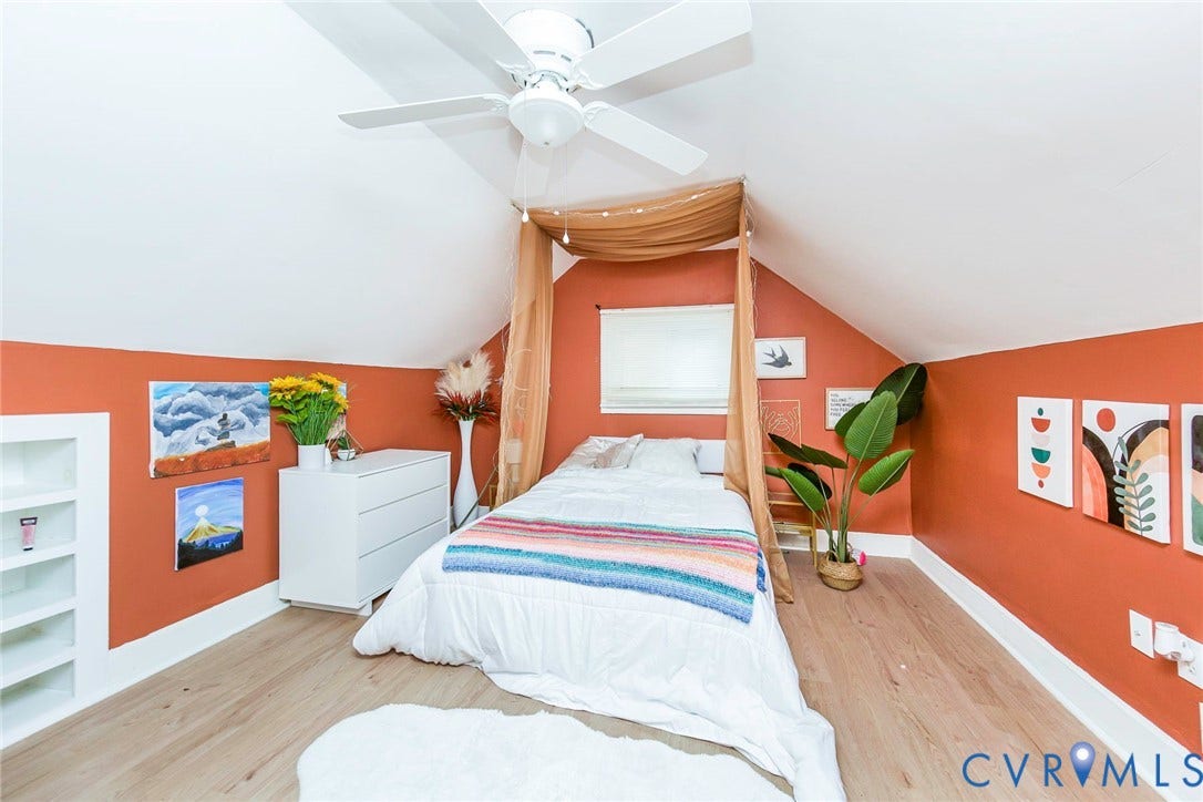 Sloped ceiling room featuring wood-finish flooring, a ceiling fan, and built-in shelving
