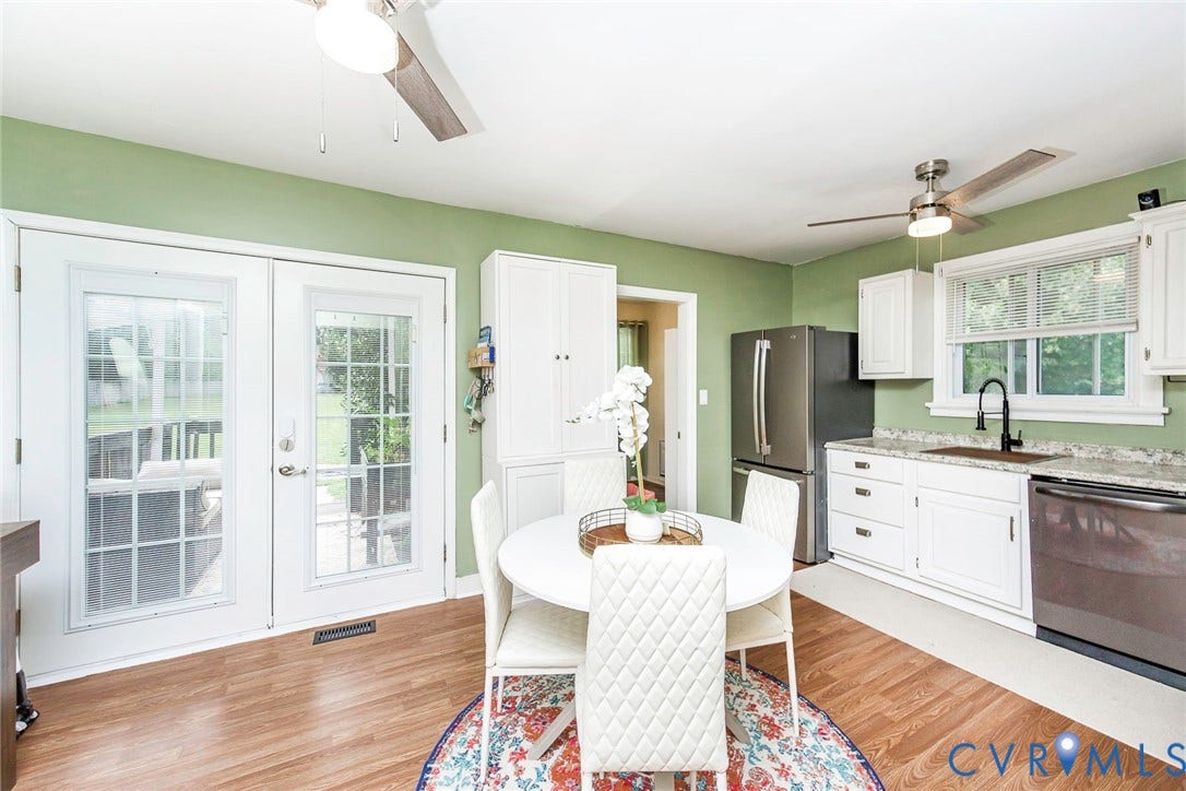 Kitchen featuring wood-finish flooring, white cabinetry, stainless steel appliances, and light-toned countertops