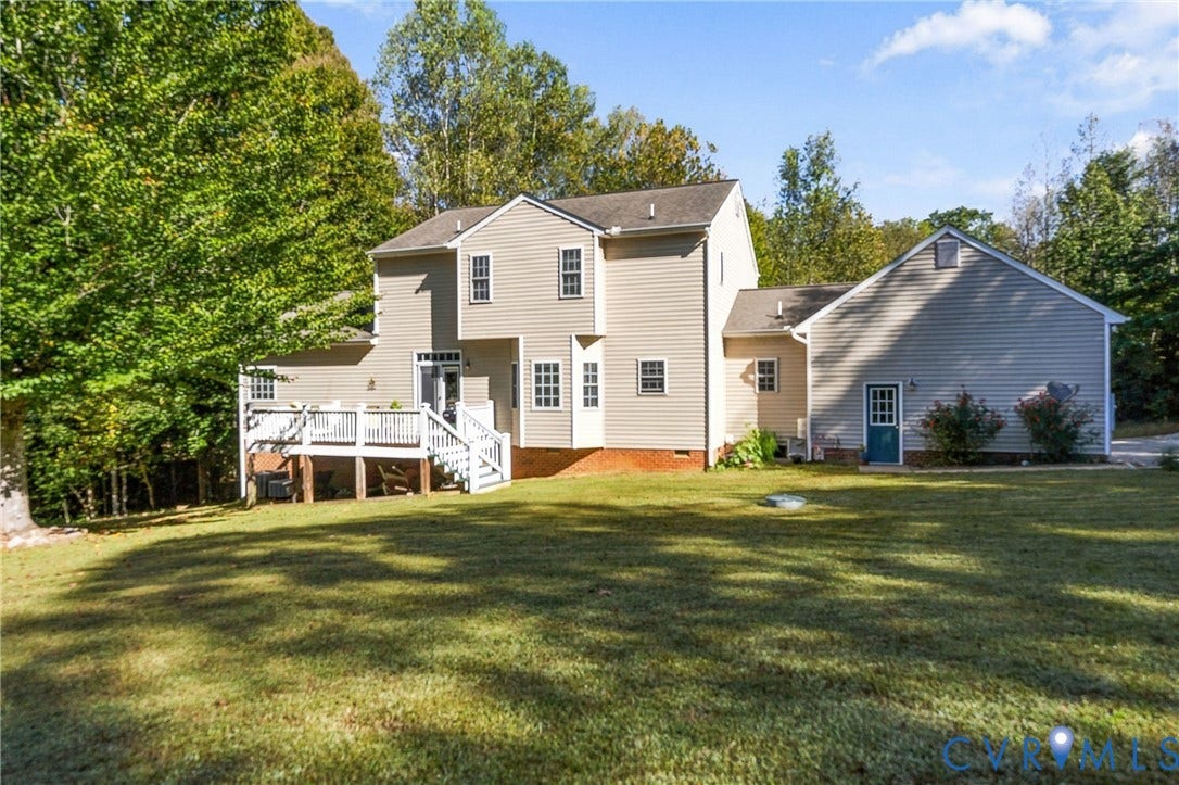 3647 Cedar Plains Road, Sandy Hook, Sandy Hook, VA 23153 Expansive rear exterior with light-colored siding, a multi-level wooden deck with white railings, multiple windows with white trim, and an attached auxiliary building with a separate entrance