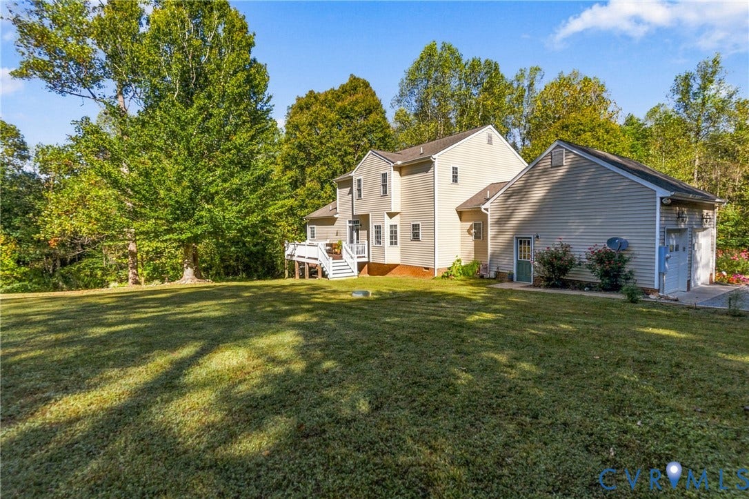 3647 Cedar Plains Road, Sandy Hook, Sandy Hook, VA 23153 Charming two-story residence with cream-colored siding and traditional architectural details, set on expansive grounds featuring a manicured lawn, mature deciduous trees, and a detached outbuilding