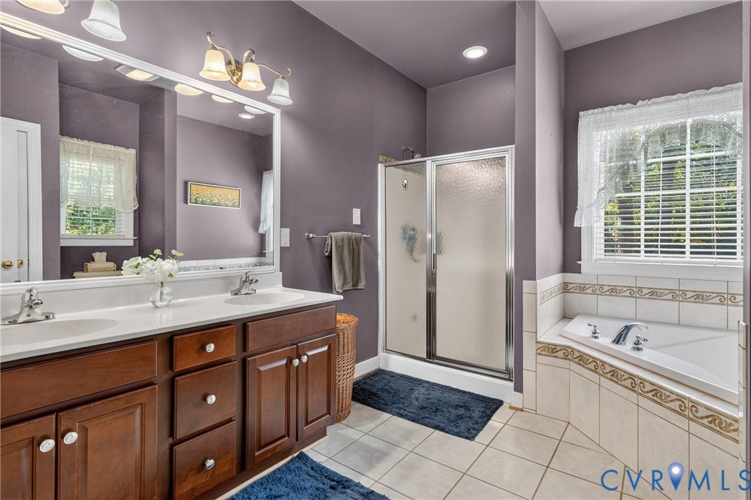 3647 Cedar Plains Road, Sandy Hook, Sandy Hook, VA 23153 Dual sink vanity with wood-finish cabinetry, a large frameless mirror, and a tiled soaking tub