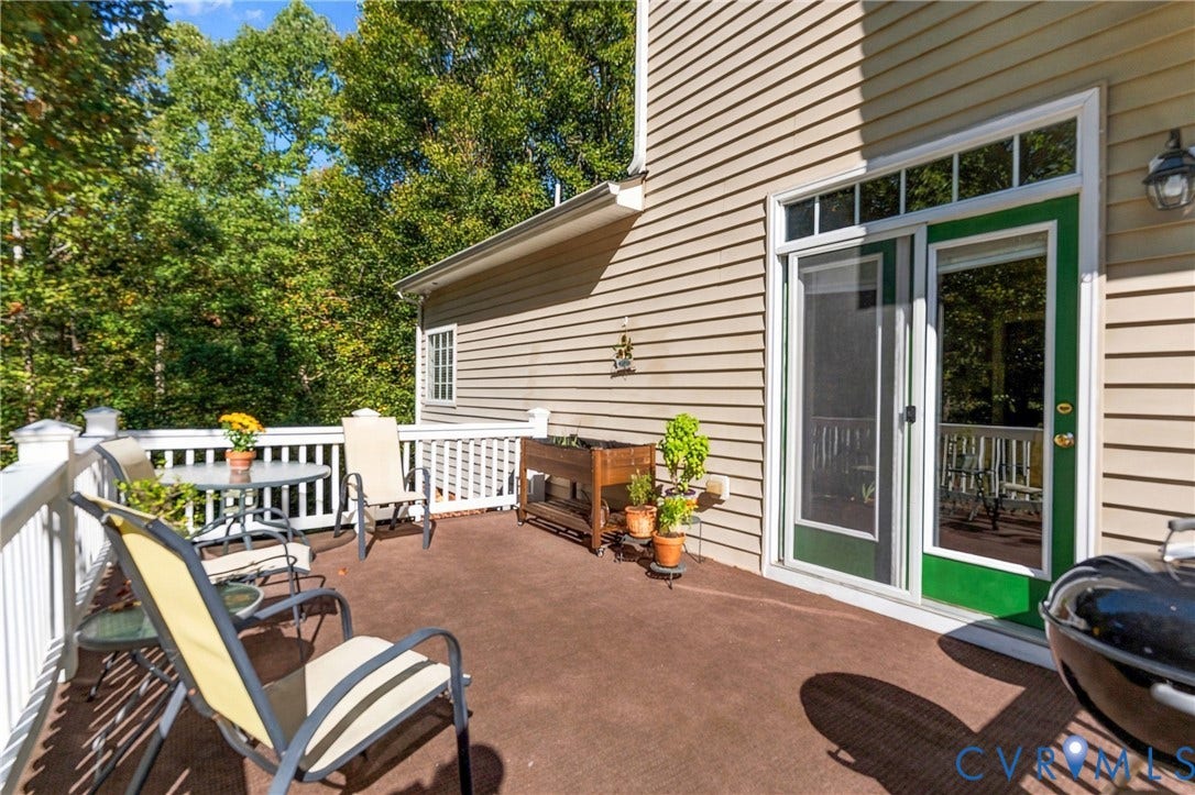 3647 Cedar Plains Road, Sandy Hook, Sandy Hook, VA 23153 Outdoor deck with white railing, featuring tan siding and a green-framed sliding glass door with transom windows
