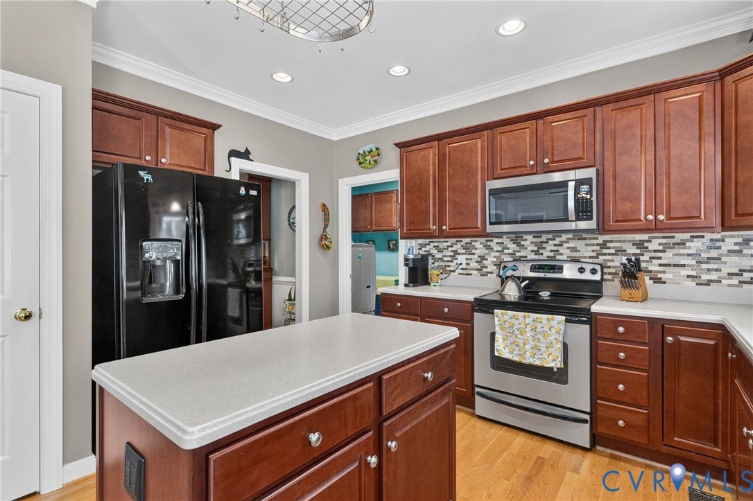 3647 Cedar Plains Road, Sandy Hook, Sandy Hook, VA 23153 Wood-finish cabinetry with a center island featuring a light-toned countertop, stainless steel appliances, mosaic tile backsplash, and recessed lighting