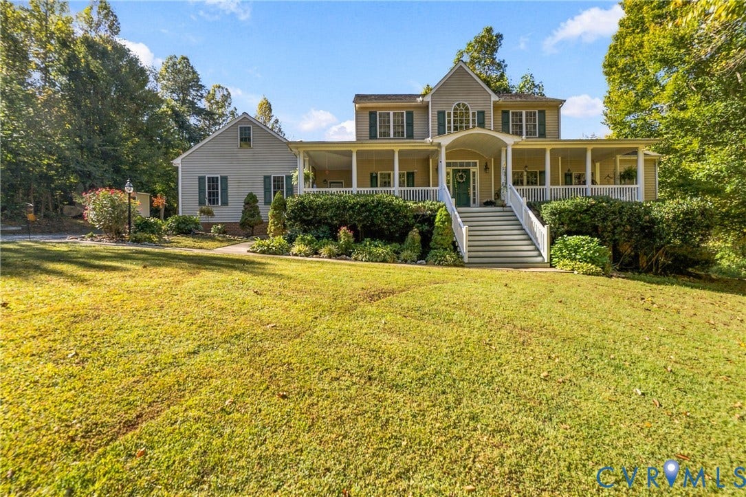 3647 Cedar Plains Road, Sandy Hook, Sandy Hook, VA 23153 Two-story residence featuring a broad wrap-around porch with white railings, a central arched entry, and a symmetrical facade with dark green shutters