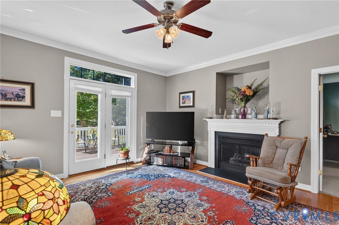 3647 Cedar Plains Road, Sandy Hook, Sandy Hook, VA 23153 Wood-finish flooring, white crown molding, ceiling fan, white French doors with transom, and a fireplace with a white mantel and hearth