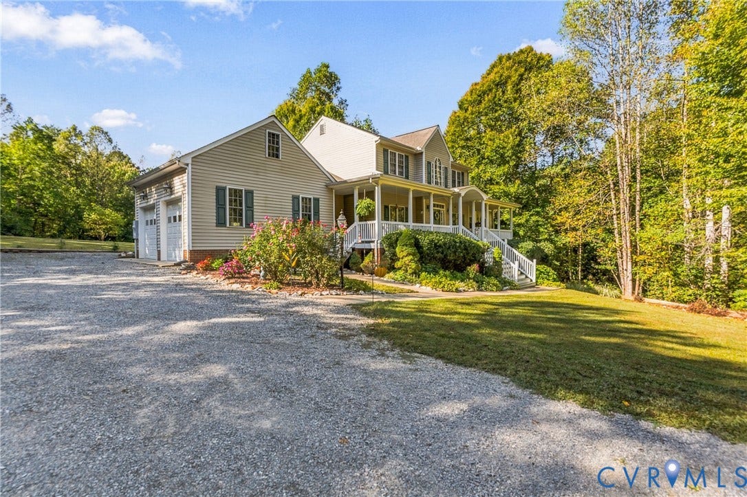 3647 Cedar Plains Road, Sandy Hook, Sandy Hook, VA 23153 Two-story residence featuring light siding, an attached two-car garage, a covered front porch, and a gravel driveway, all surrounded by mature trees