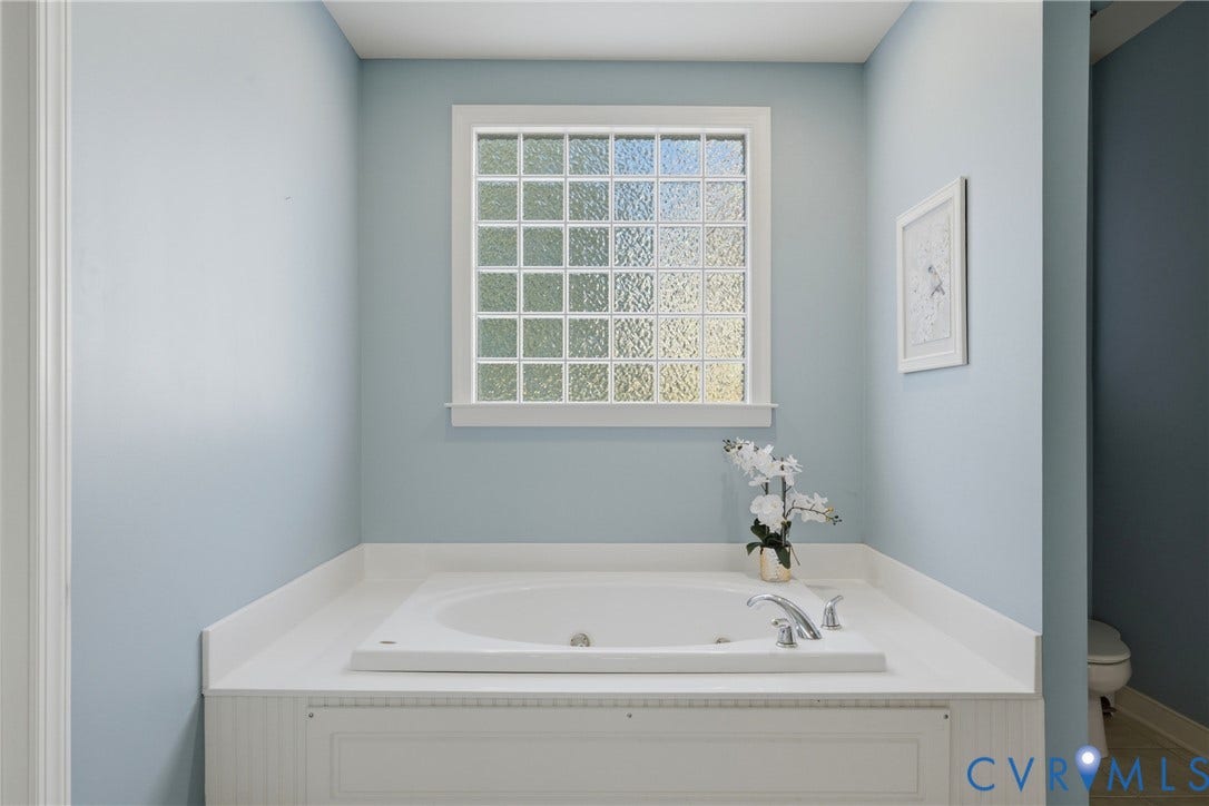 11813 Longfellow Drive, Bayhill Pointe, Midlothian, VA 23112 Built-in soaking tub with a white surround, featuring a grid-pattern glass block window and chrome-finish hardware