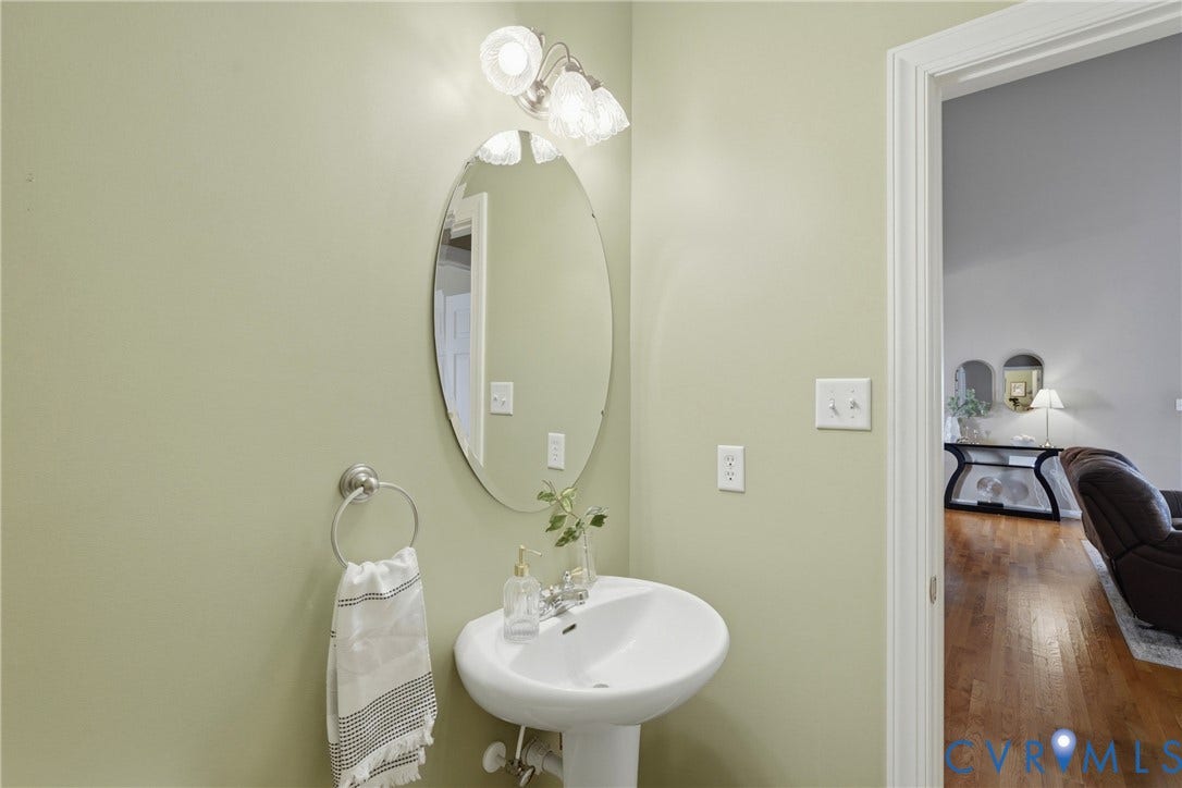 11813 Longfellow Drive, Bayhill Pointe, Midlothian, VA 23112 Pedestal sink with polished metal faucet, oval wall-mounted mirror, and multi-bulb decorative light fixture