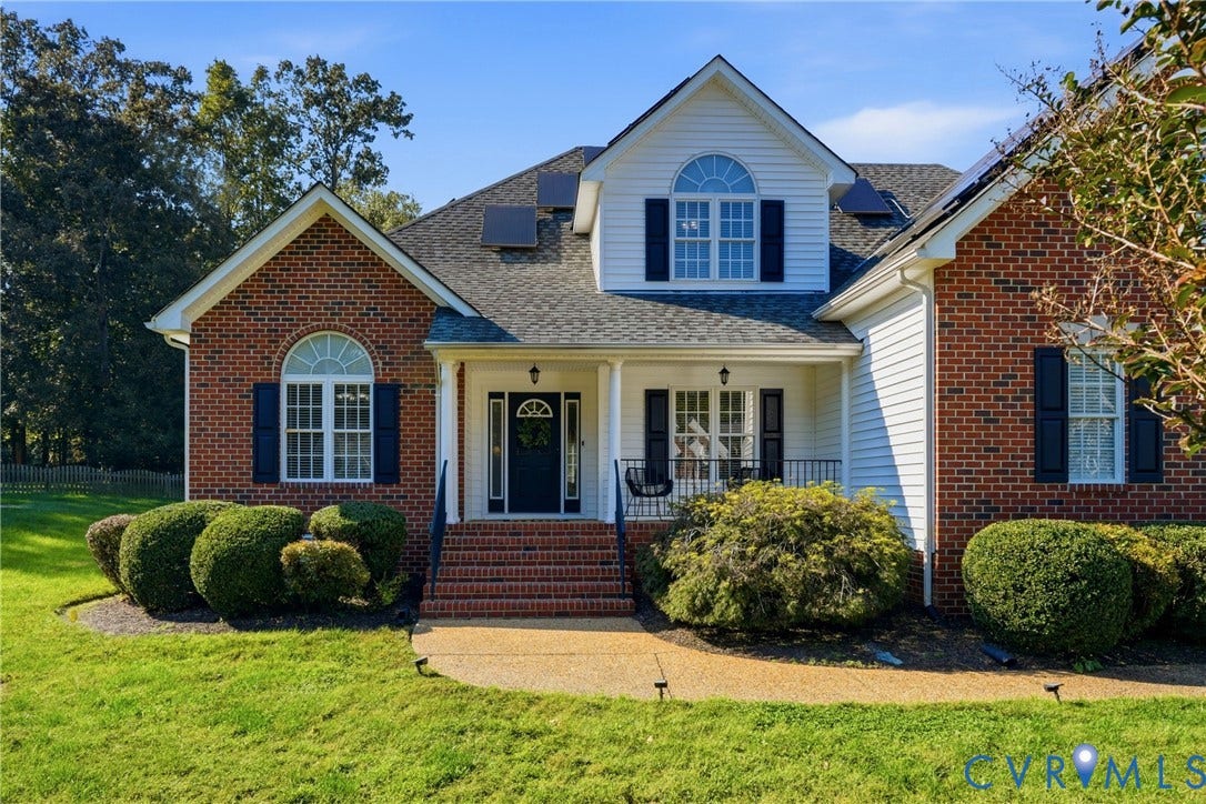 11813 Longfellow Drive, Bayhill Pointe, Midlothian, VA 23112 Multi-gabled brick and vinyl siding exterior featuring arched windows, a covered front porch with iron railing, brick entry steps, and roof-integrated solar panels