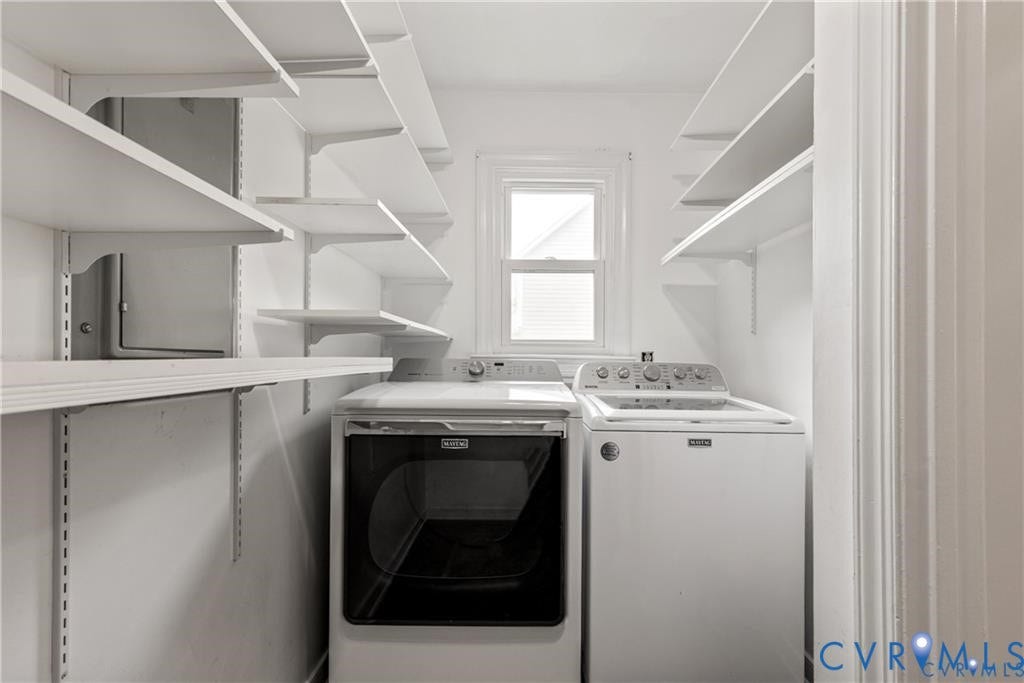 Dedicated laundry area featuring a window, built-in shelving, and a white appliance set