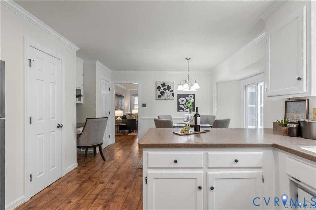 Kitchen with white cabinetry, brown countertops, and wood-finish flooring