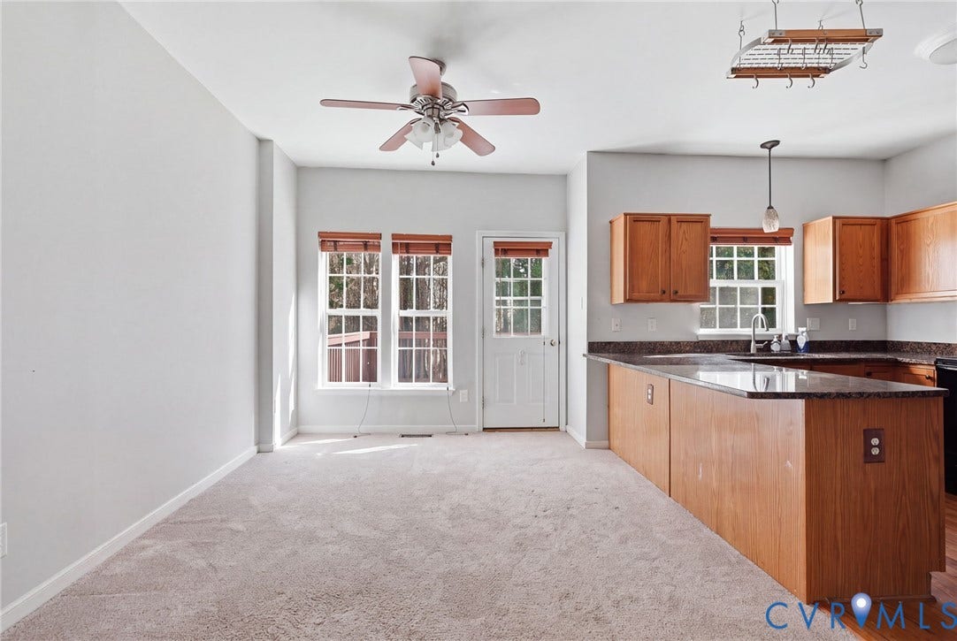 2803 Queensland Drive, #2803, Pemberton Oaks, Glen Allen, VA 23294 Kitchen featuring wooden cabinetry, dark stone-finish countertops, a breakfast bar, and a ceiling-mounted pot rack, complemented by a ceiling fan with integrated lighting