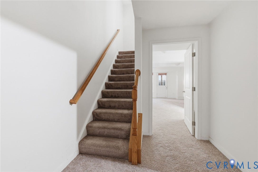 2803 Queensland Drive, #2803, Pemberton Oaks, Glen Allen, VA 23294 Staircase with carpeted treads, wood-finish handrail, and wooden baluster, featuring neutral-toned carpeting and a multi-panel interior door