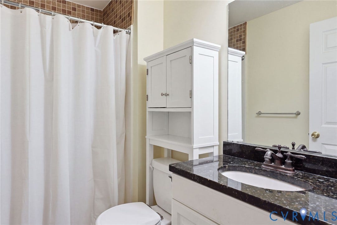 2803 Queensland Drive, #2803, Pemberton Oaks, Glen Allen, VA 23294 Bathroom featuring a stone-top vanity with an integrated oval sink, dark metal faucet, full-width mirror, and decorative tile accents surrounding the shower area