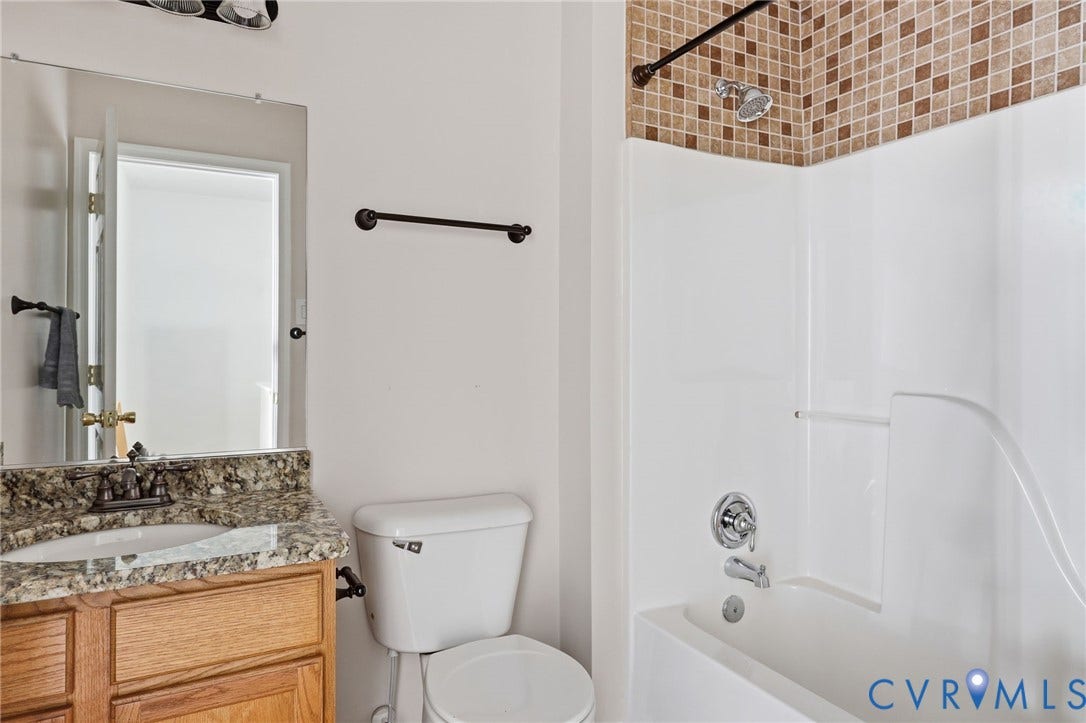2803 Queensland Drive, #2803, Pemberton Oaks, Glen Allen, VA 23294 Bathroom featuring a vanity with stone-finish countertop, undermount sink, multi-tone mosaic tile shower surround, white composite tub, and dark hardware