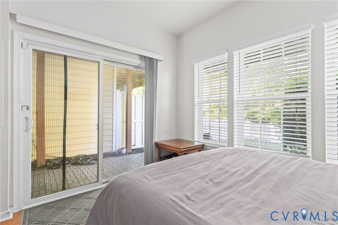 Sliding glass door access to an outdoor area, complemented by multiple windows with blinds