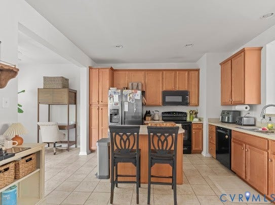 Kitchen featuring tile flooring, wood cabinetry, a central island, and recessed lighting