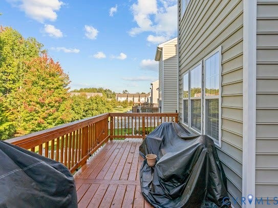 Spacious exterior deck with wood-finish flooring and railing, complemented by siding and multiple windows