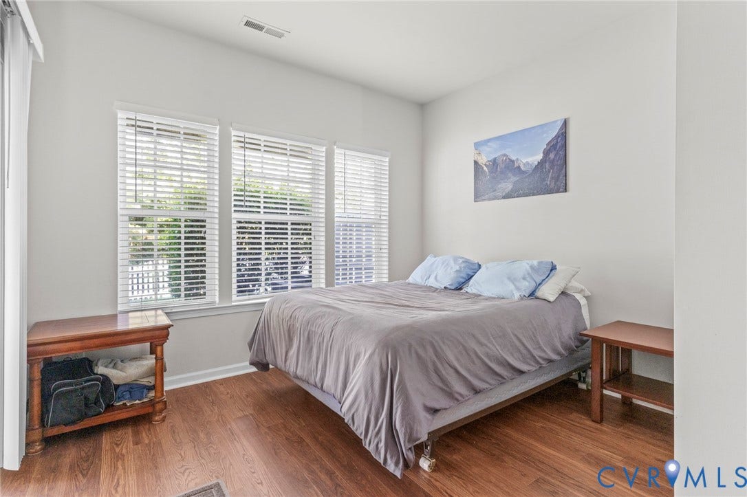Wood-finish flooring with white baseboards, multiple windows, and a neutral wall color