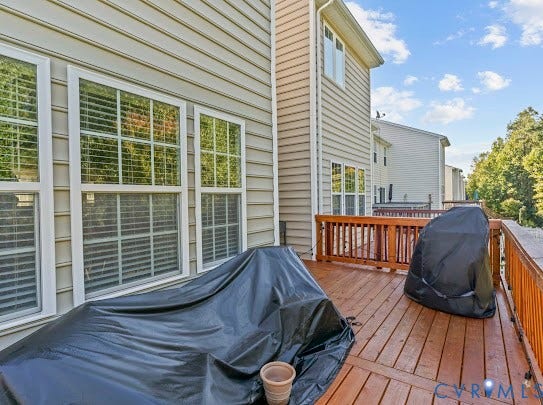 Exterior deck with wood railing, siding facade, and multiple windows