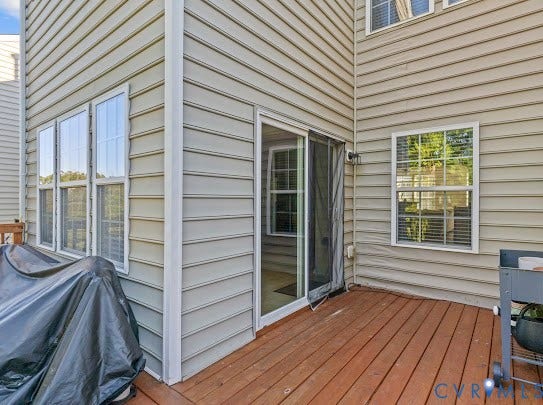 Hardwood deck with a sliding glass door, multiple windows, and horizontal siding