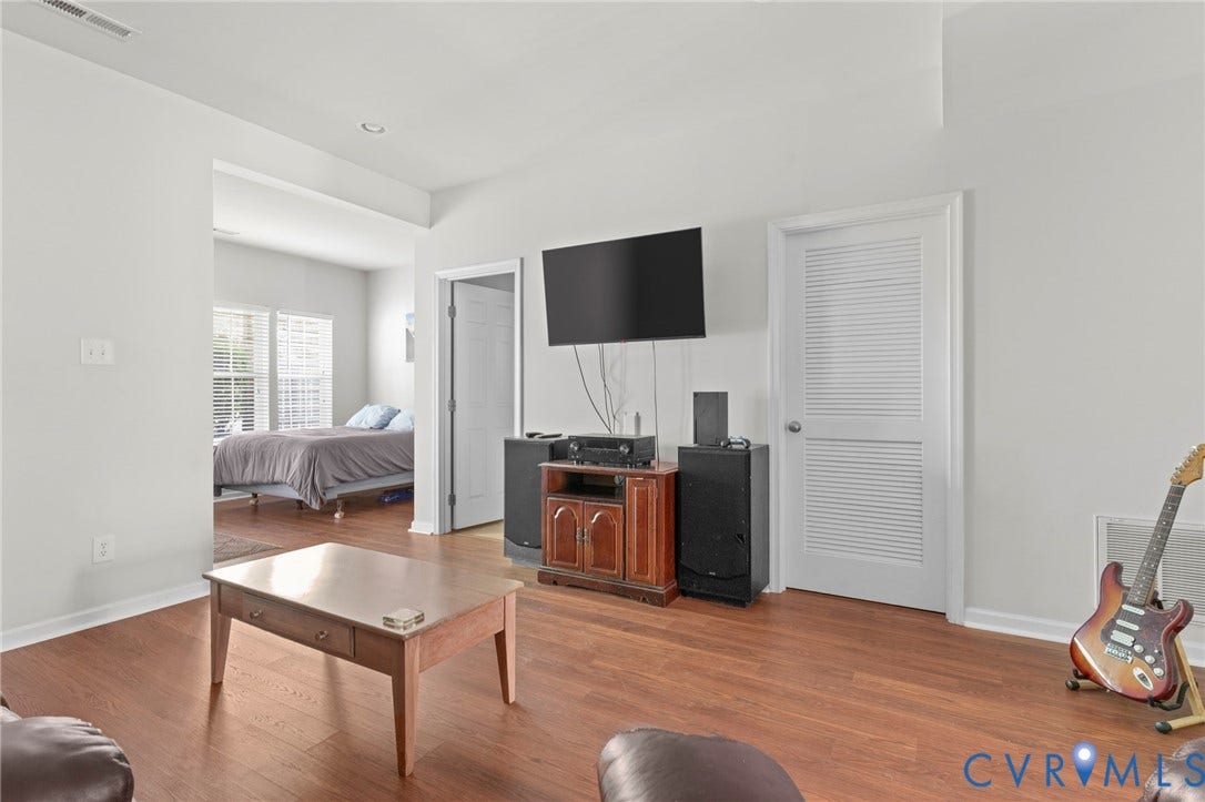 Wood-finish flooring throughout, white painted walls, and an overhead recessed light fixture